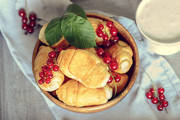 Image showing Croissants with currant berries on a wooden tray. The concept of a wholesome breakfast.