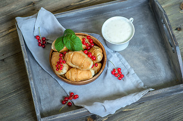 Image showing Croissants with currant berries on a wooden tray. The concept of a wholesome breakfast.