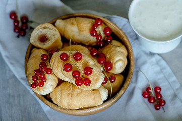 Image showing Croissants with currant berries on a wooden tray. The concept of a wholesome breakfast.