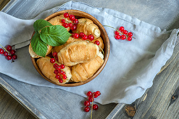 Image showing Croissants with currant berries on a wooden tray. The concept of a wholesome breakfast.