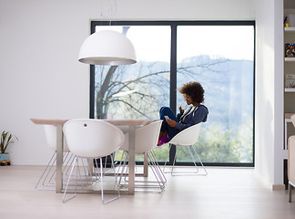 Image showing black woman drinking coffee and using a mobile phone  at home