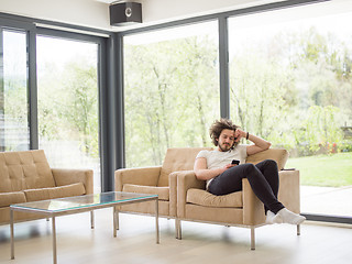 Image showing young man using a mobile phone  at home