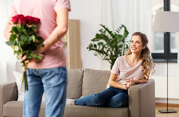 Image showing woman looking at man with bunch of flowers at home