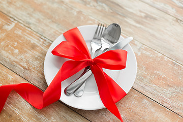 Image showing cutlery tied with red ribbon on set of plates