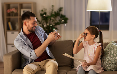 Image showing father photographing daughter by cellphone at home