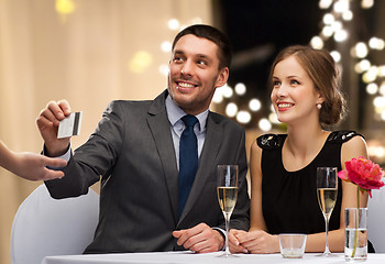 Image showing happy couple at restaurant paying by credit card