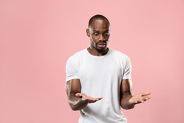 Image showing Beautiful male half-length portrait isolated on pink studio backgroud. The young emotional surprised man