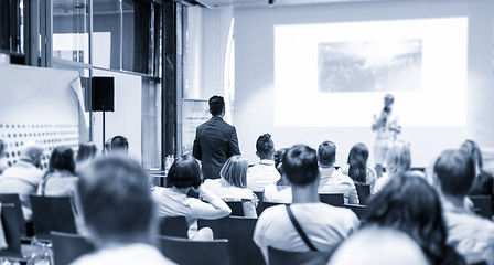 Image showing Businessman in audience standing and asking question to speeker at business conference.