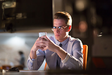 Image showing man using mobile phone in dark office