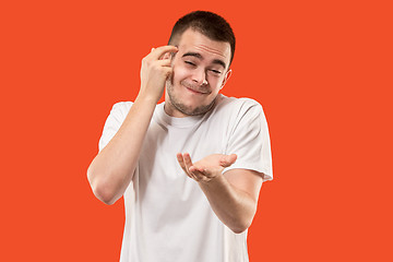 Image showing Beautiful male half-length portrait isolated on orange studio backgroud. The young emotional surprised man