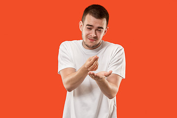 Image showing Beautiful male half-length portrait isolated on orange studio backgroud. The young emotional surprised man