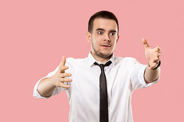 Image showing Beautiful male half-length portrait isolated on pink studio backgroud. The young emotional surprised man