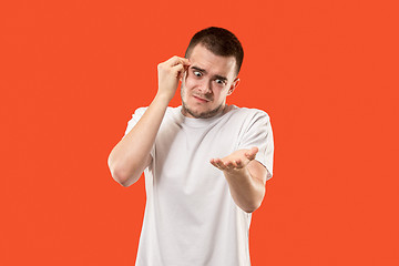 Image showing Beautiful male half-length portrait isolated on orange studio backgroud. The young emotional surprised man