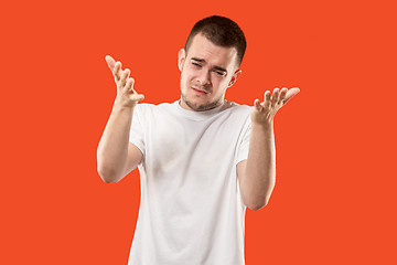 Image showing Beautiful male half-length portrait isolated on orange studio backgroud. The young emotional surprised man