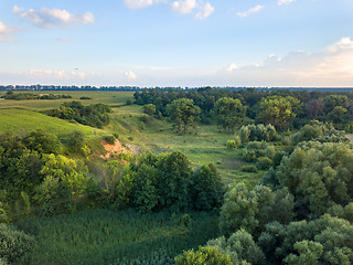 Image showing Aerial view from the drone of a natural landscape with greenery, forest, field, ravine on a background of a cloudy sky.