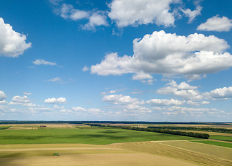 Image showing Summer landscape with agricultural fields, harvesting on a backgground of the blue sky and white clouds in a sunny day. View from drone.