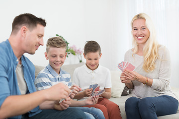 Image showing Happy young family playing card game at home.