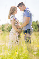 Image showing Young happy pregnant couple hugging in nature.