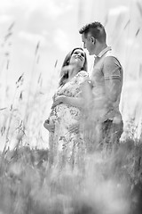 Image showing Young happy pregnant couple hugging in nature.