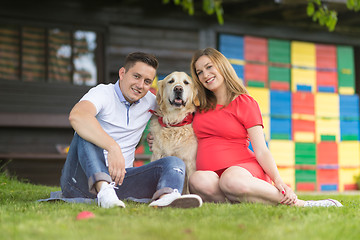 Image showing A Young couple expecting baby with their Golden retriever dog