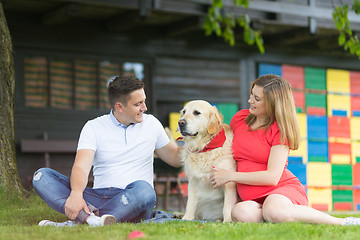 Image showing A Young couple expecting baby with their Golden retriever dog