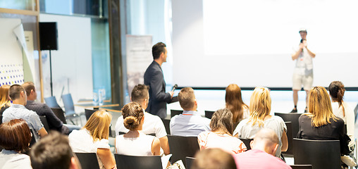 Image showing Businessman in audience standing and asking question to speeker at business conference.