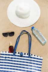 Image showing beach bag, sunscreen, sunglasses and hat on sand