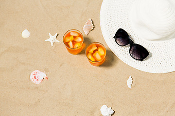 Image showing cocktails, sun hat and sunglasses on beach sand