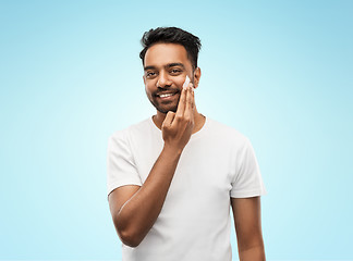 Image showing happy indian man applying cream to face