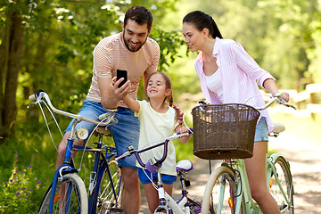 Image showing family with smartphone and bicycles in summer park