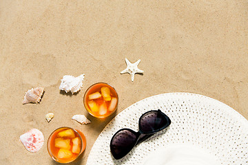 Image showing cocktails, sun hat and sunglasses on beach sand