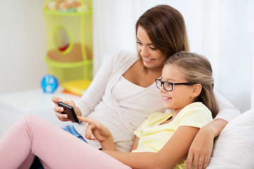 Image showing happy mother and daughter with smartphone at home