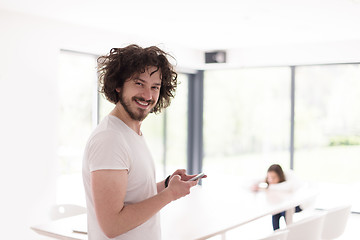 Image showing young man using a mobile phone  at home