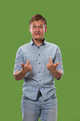 Image showing The young attractive man looking suprised isolated on green