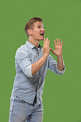 Image showing Isolated on green young casual man shouting at studio