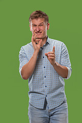 Image showing The young man whispering a secret behind her hand over green background