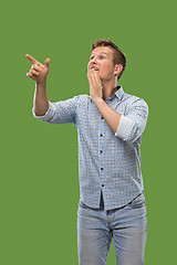 Image showing Isolated on green young casual man shouting at studio