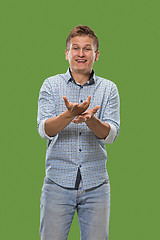 Image showing Beautiful male half-length portrait isolated on green studio backgroud. The young emotional surprised man