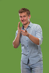 Image showing The young man whispering a secret behind her hand over green background