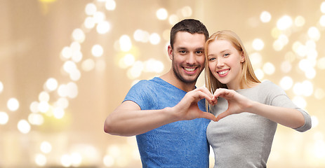 Image showing couple showing hand heart over festive lights