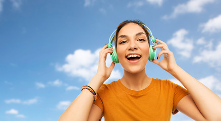 Image showing teenage girl in earphones over sky