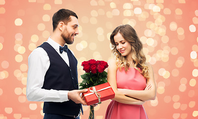 Image showing happy man giving woman flowers and present