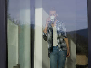 Image showing young woman drinking morning coffee by the window