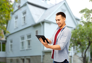 Image showing happy young man with tablet computer over house