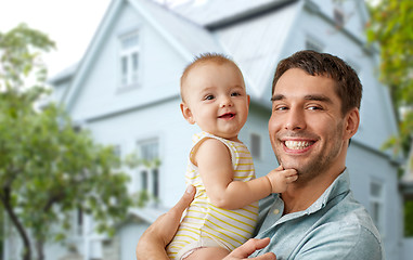 Image showing happy father holding baby daughter over house