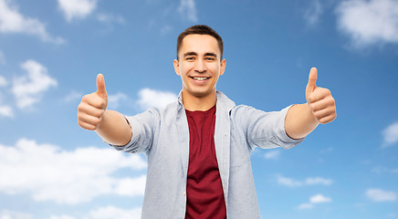 Image showing happy young man showing thumbs up over blue sky