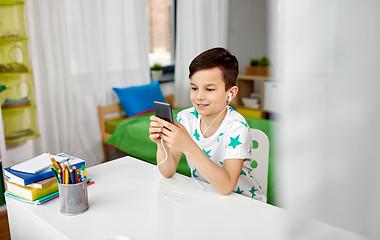 Image showing boy in earphones listening to music on smartphone