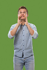 Image showing Isolated on green young casual man shouting at studio