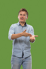 Image showing Beautiful male half-length portrait isolated on green studio backgroud. The young emotional surprised man