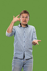 Image showing Beautiful male half-length portrait isolated on green studio backgroud. The young emotional surprised man